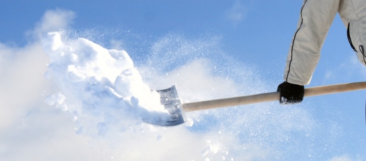 Une personne en train de déneiger son toit avec une pelle à neige